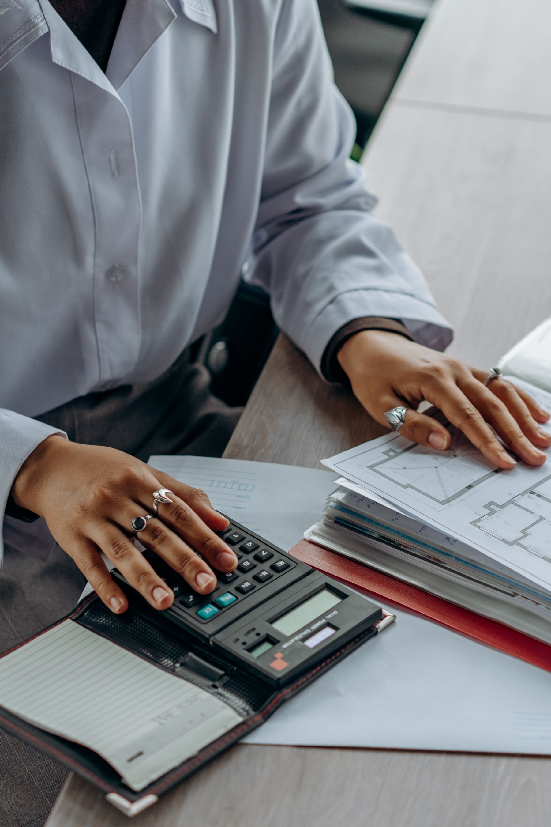 Person reviewing financial documents with a calculator on a desk